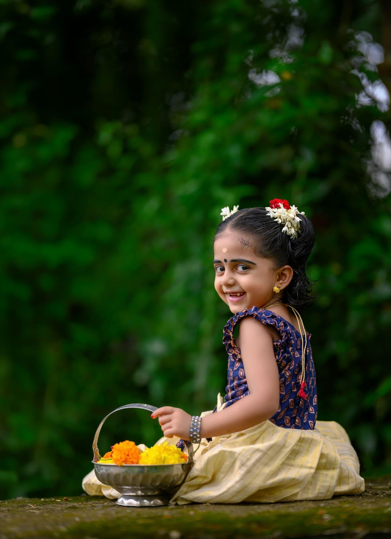 Little girl in a cream silk pavadai with a navy blouse, holding a flower basket — view 2 of 2