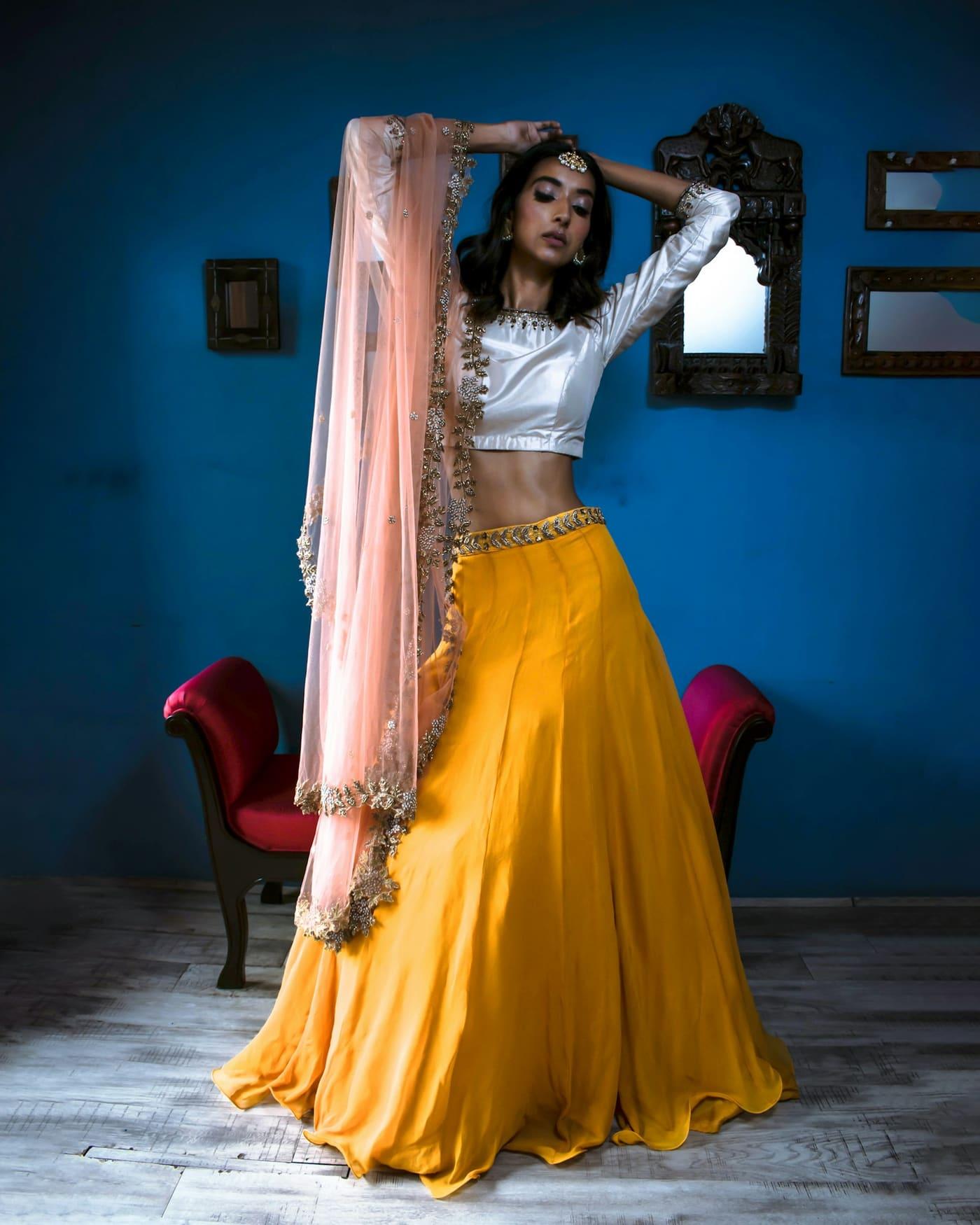 Woman in a mustard chaniya with an ivory choli and a sheer dupatta