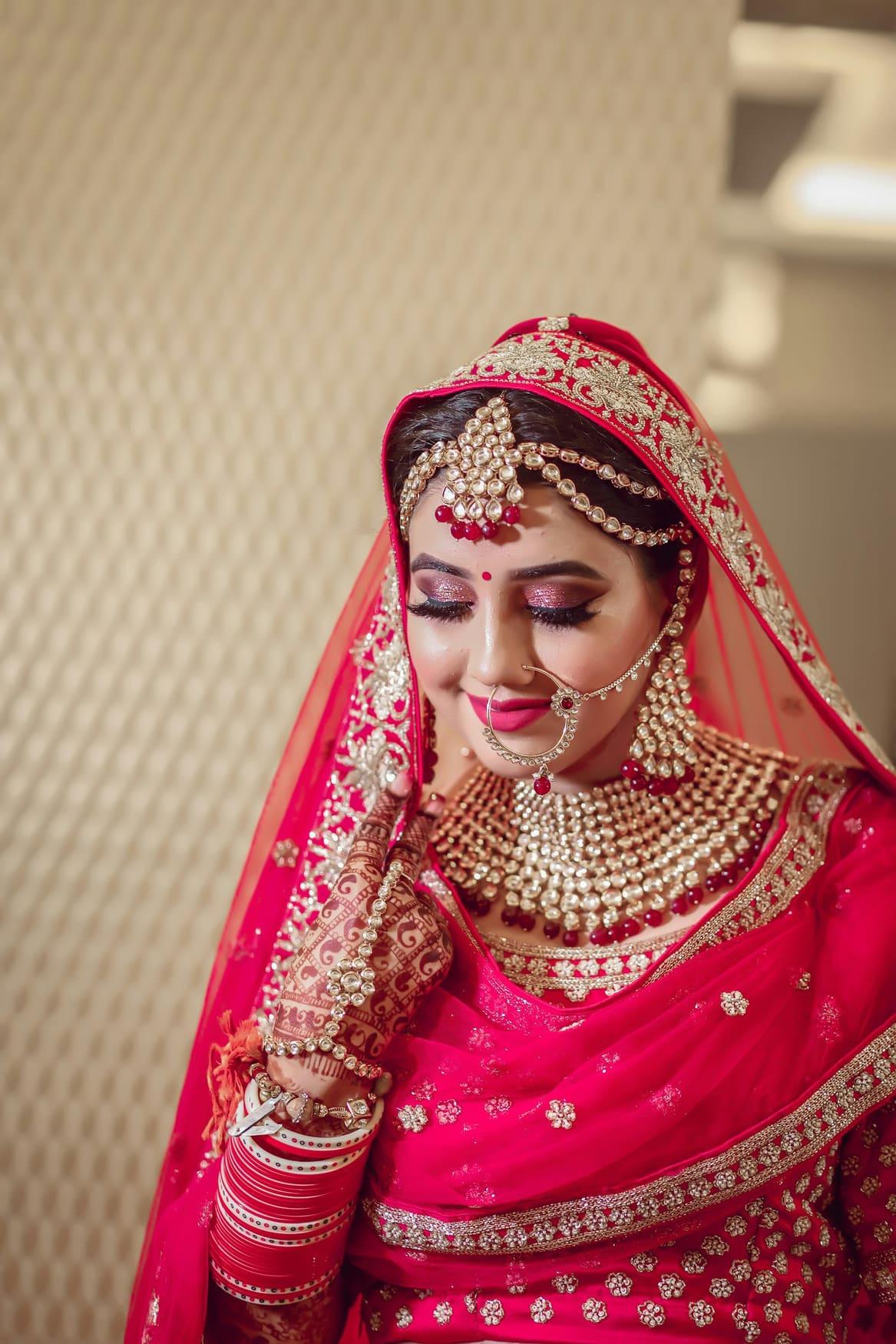 Bride in a rani pink lehenga with gold zardozi embroidery and kundan jewellery — view 2 of 3