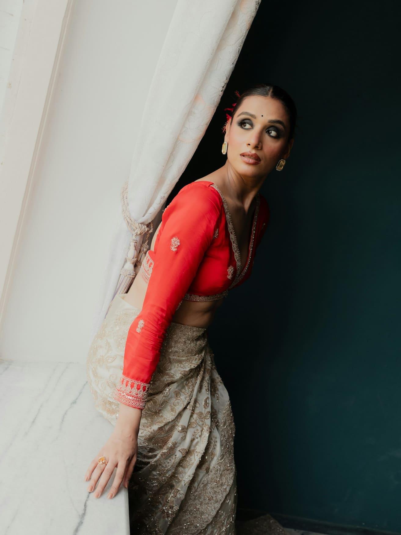 Woman in a red long-sleeve silk blouse and gold tissue saree