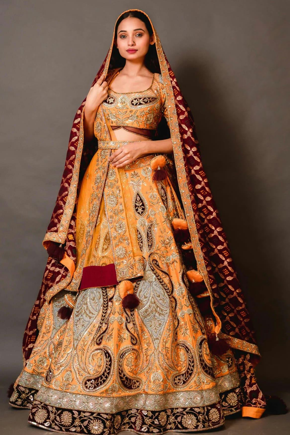 Woman in a saffron and maroon embroidered lehenga choli with a red dupatta