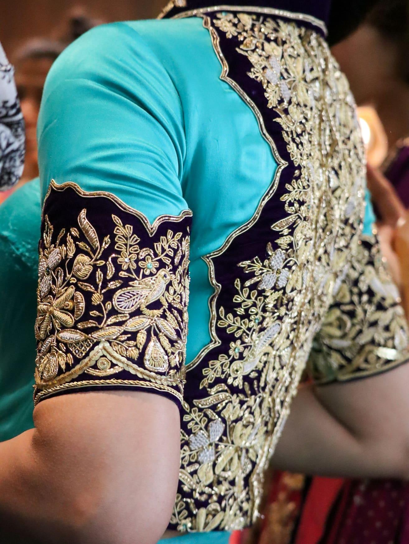 Close-up of a turquoise silk blouse sleeve with gold zari embroidery